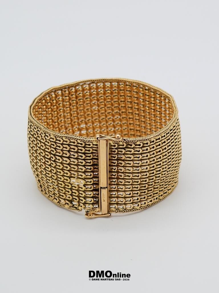Gold-tone wide mesh bracelet with a hinged rectangular clasp on a light background, close-up view.