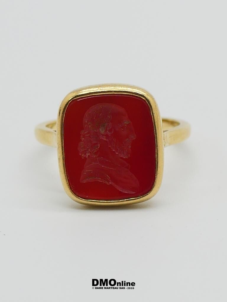 Gold ring with a red rectangular cabochon featuring a carved-profile cameo of a bearded man on a white background