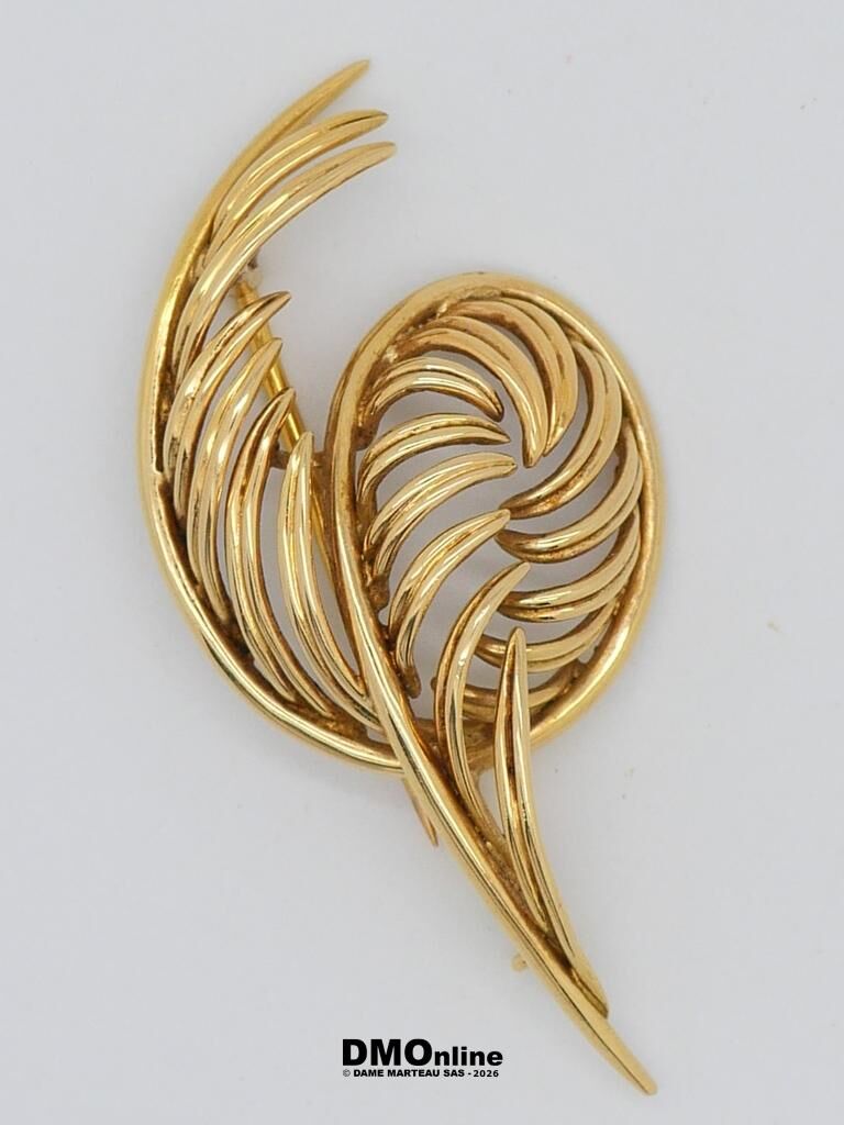Gold-tone feather-shaped brooch with curved overlapping leaflets on a white background.