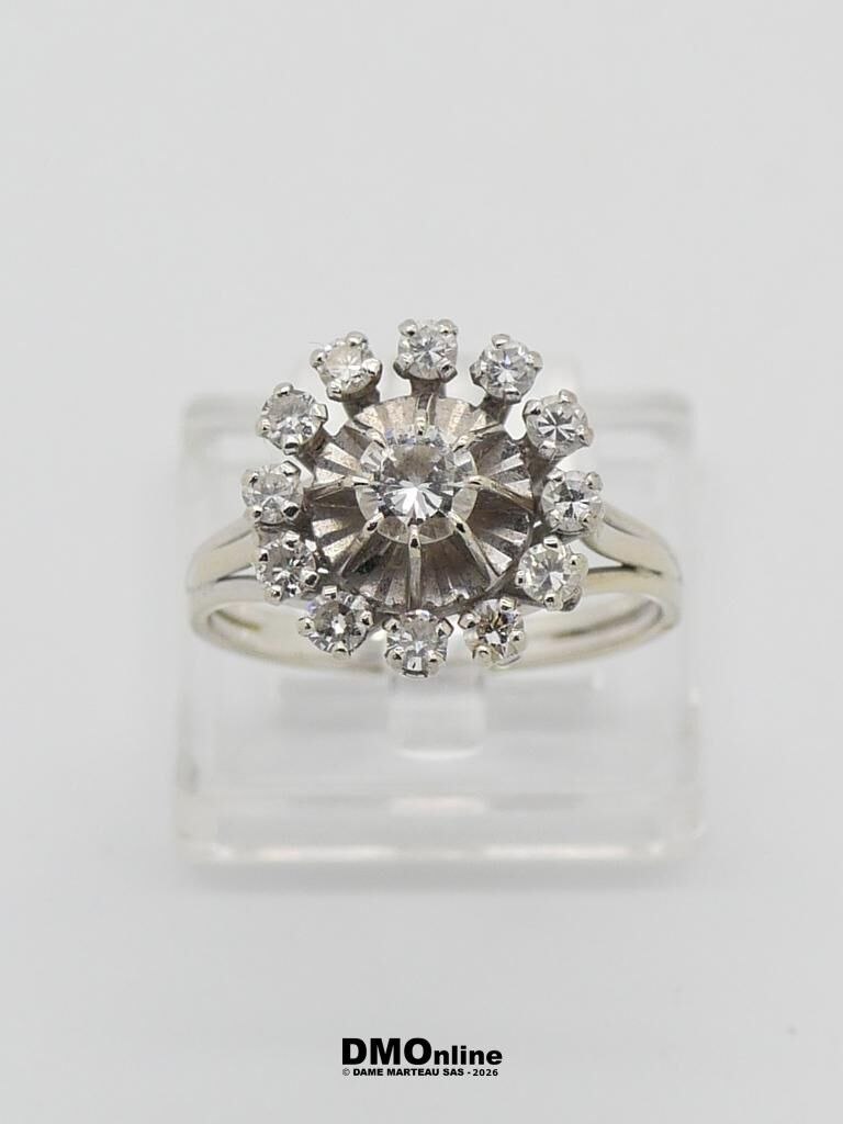 Silver halo diamond ring on a clear display stand, with a center stone surrounded by small pavé diamonds and a polished band.