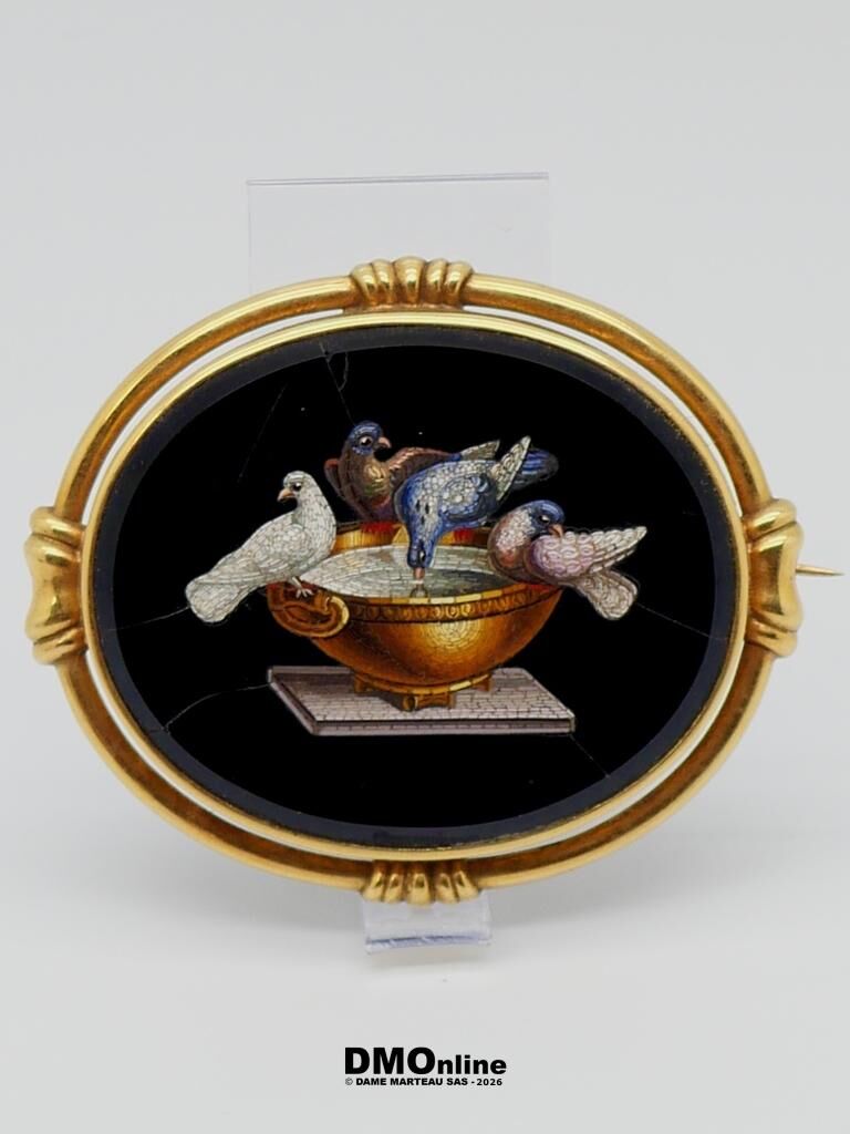Round gold-framed artwork showing four pigeons perched on a golden bowl on a pedestal against a black background.